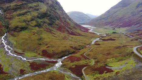 Dramatische-Luftaufnahme-Des-Glencoe-Gebirges-Mit-Schwenk-Nach-Rechts,-Zeigt-Fließende-Flüsse-Und-Hebt-Die-Palette-Der-Verschiedenen-Farben-Hervor