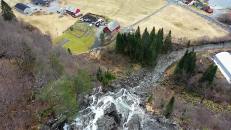 Aerial-from-Kvernhusfossen-waterfall,-tilt-up-revealing-MO-in-Modalen-Norway