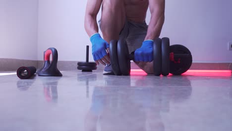 man-taking-apart-dumbbells-after-weightlifting-session