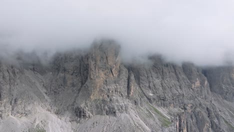 Luftaufnahmen-Einer-Drohne-Fangen-Die-Schroffen-Gipfel-Des-Grödnerjochs-Ein,-Die-In-Wolken-Gehüllt-Sind,-Während-Die-Drohne-Aufsteigt-Und-Nach-Rechts-Abbiegt