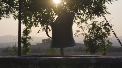 well-metal-old-bucket-close-up-in-countryside-of-Tuscany-Italy-with-sunshine-from-the-scenic-landscape-hills