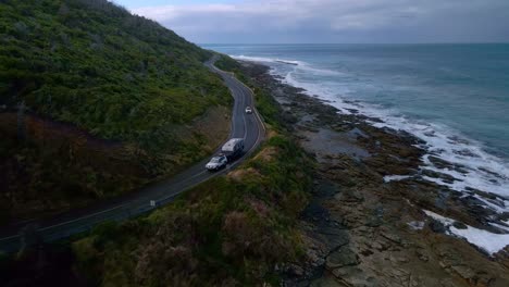 White-SUV-with-caravan-trailer-drives-along-curved-corner-of-Australia'-Great-Ocean-Road-in-Victoria