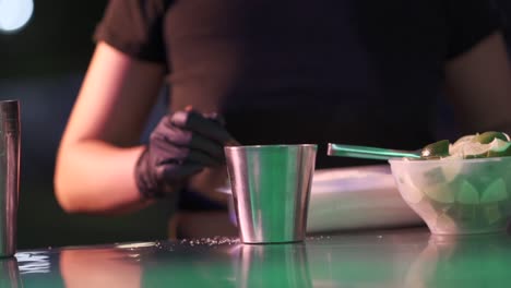 A-woman-prepares-cocktail-recipe-with-sugar-and-lemon-in-a-metal-container