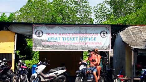 Tourists-On-Motorbike-Stops-At-Ferry-Boat-Ticket-Office-In-Nusa-Lembongan-To-Nusa-Penida-In-Bali,-Indonesia