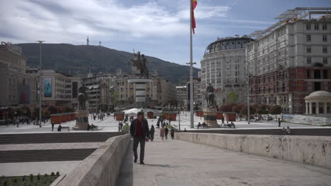 Hombre-Cruzando-El-Puente-De-Piedra-De-Skopje-En-Un-Día-Soleado,-Plaza-De-Macedonia-Del-Norte