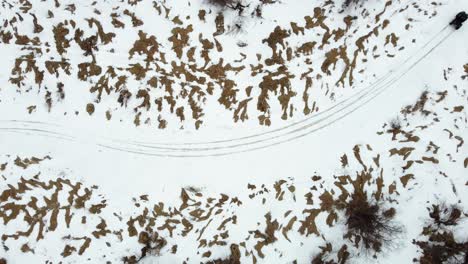 Aerial-top-down-view-of-an-ATV-drifting-around-a-corner-on-a-frozen-river-trail