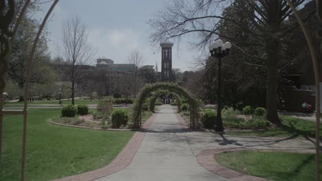 -Eine-Mittlere-Aufnahme-Durch-Einen-Verzierten-Pavillon-Auf-Einen-Mit-Bögen-Gesäumten-Weg-Und-Einen-Hohen,-Schmalen-Turm-In-Der-Ferne-In-Nashville,-Umgeben-Von-üppigem-Grün-Und-Einem-Klaren-Himmel