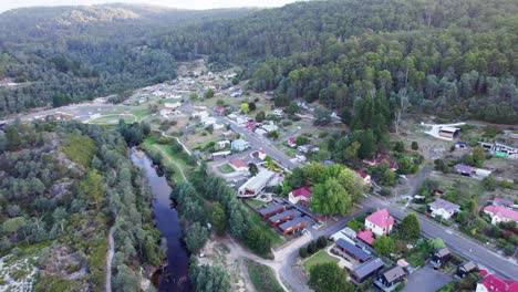 Aerial-regional-town-surrounded-by-forest-Derby,-Tasmania,-Australia