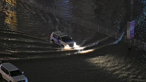On-April-16,-2024,-a-rescue-vehicle-navigates-through-rain-on-a-flooded-road-at-night-in-Sharjah,-UAE,-after-record-breaking-rains-hit-the-country