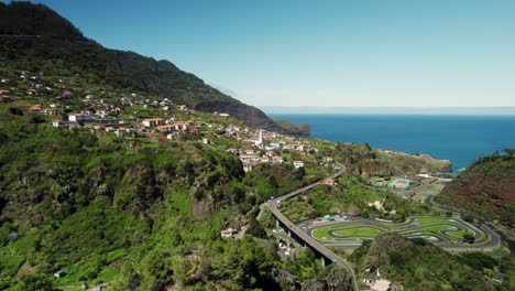 Imágenes-De-Drones-Del-Paisaje-Del-Pueblo-De-Madeira,-Una-Carretera-Con-Curvas-Y-El-Océano-Al-Fondo