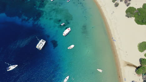 Aerial:-Sailboats-and-catamarans-on-Tsougria-island-beach-near-Skiathos,-Sporades,-Greece