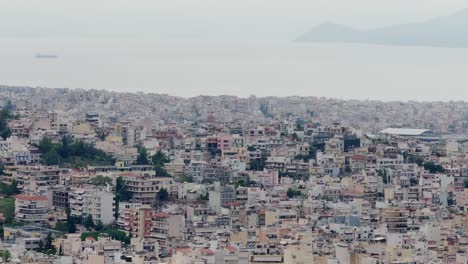 Imágenes-Aéreas-De-Un-Día-Nublado-Y-De-Mal-Humor-Del-Centro-De-La-Ciudad-De-Atenas,-Grecia,-Con-Vistas-Al-Mar-Al-Fondo