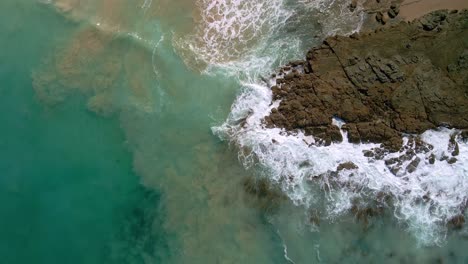 Drone-view-of-ocean-waves-crashing-against-rocky-beach-near-Wye-River-town-in-Victoria,-Australia