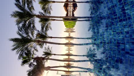 Vertical-View-Of-Mirror-Reflection-Of-Palm-Trees-In-The-Pool-At-The-Luxury-Beach-Hotel-Resort