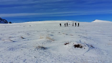 A-group-of-people-hiking-in-snow-covered-highlands-on-a-sunny-cold-winter-day