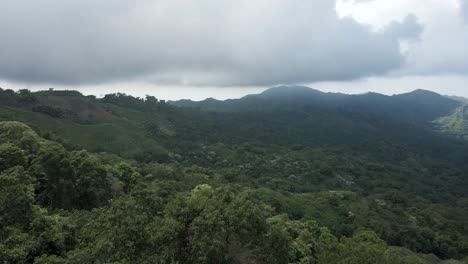 Drone-passes-by-the-Colombian-flag-to-pan-over-the-forested-canopy-with-the-Sierra-Nevada-in-the-background