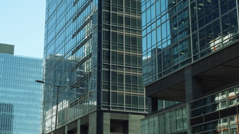 Las-Paredes-Modernas-Están-Hechas-De-Vidrio-Y-Acero-Con-Reflejos-De-Edificios-Y-Cielo-Azul.