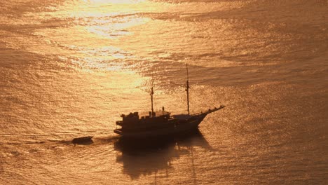 Silhouette-of-sailing-ship-navigating-in-open-sea-at-sunset