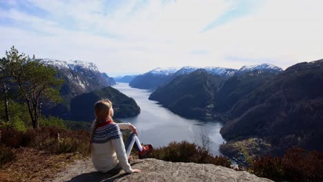Young-woman-arrives-at-Veafjord-viewpoint,-sits-down-to-enjoy-view-and-stretch-legs,-Norway