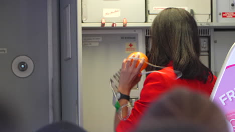 Asian-stewardess-showing-the-use-of-oxygen-mask-on-aircraft