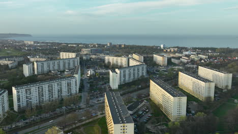 Aerial-view-of-apartment-blocks-in-a-city,-with-a-glimpse-of-the-sea-in-the-distance,-during-late-afternoon-light