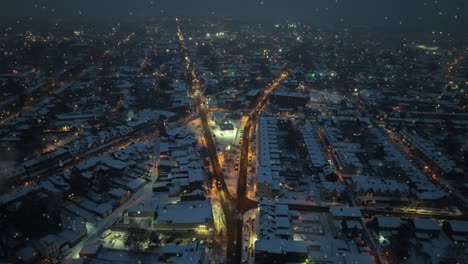 Snowy-urban-crossroads-at-night,-glowing-street-lights,-residential-area,-serene-atmosphere