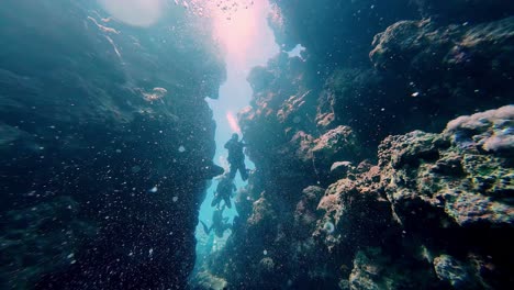 Taucher-Schwimmt-Zwischen-Kantigen-Schmalen-Felsklippen-Unterwasseraufnahme-In-Dahab,-Ägypten