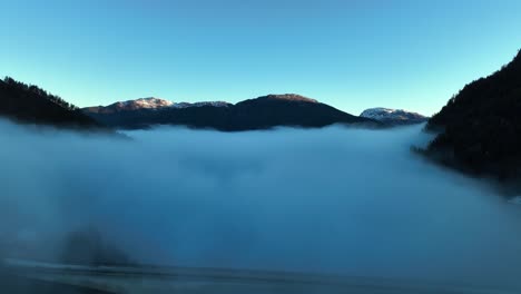 Puente-Kallestadsundet-Y-Montañas-De-Noruega-Vistas-Sobre-La-Neblina-Matutina,-Cielo-Azul-Aéreo-Matutino