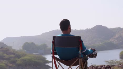 isolated-man-sitting-at-camping-chair-at-mountain-top-with-lake-view-at-morning