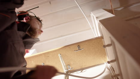 Electrician-places-mains-cable-along-wall-and-behind-shelf,-upwards-shot