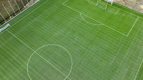 Top-down-aerial-view-of-a-football-pitch-with-freshly-painted-lines-and-goalposts,-set-against-a-backdrop-of-trees-with-no-players-in-sight