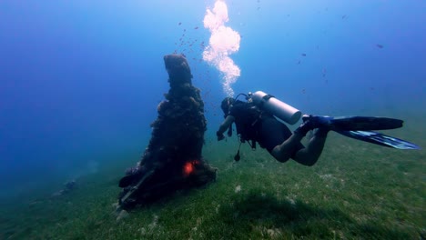 Scuba-diving-underwater-slow-perspective-of-diver-breathing-bubbles-in-Egypt-around-coral-stones-and-fish-in-blue-water-element