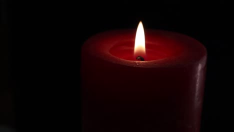 Burning-red-candle-on-turntable-isolated-on-black-background