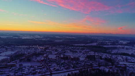 Gradient-colorful-sunset-pink-blue-skyline-above-frozen-city-winter-town-location-houses-below-white-freezing-village,-establishing-shot