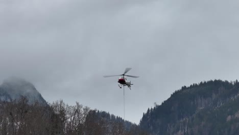 Helicopter-carrying-load-over-Amden,-Glarus,-Switzerland