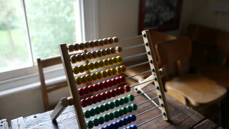 Brightly-colored-abacus-on-aged-wooden-desk,-a-symbol-of-traditional-education-and-arithmetic