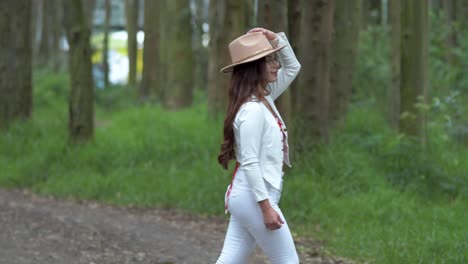 Beautiful-woman-walks-through-nature-and-puts-a-hat-on-her-head