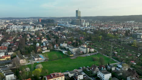 Expansive-aerial-view-over-a-mixed-urban-landscape-with-residential-houses,-towering-office-buildings,-and-green-spaces---OBC,-Oliwa,-Gdańsk