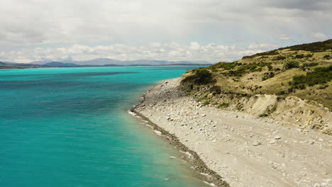 Flying-along-the-coast-of-the-expansive-Lake-Pukaki,-South-Island,-New-Zealand