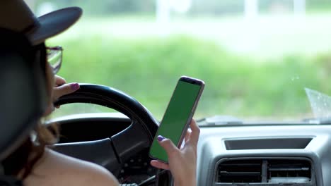 Over-shoulder-view-of-girl-in-car-behind-wheel-scrolling-on-phone
