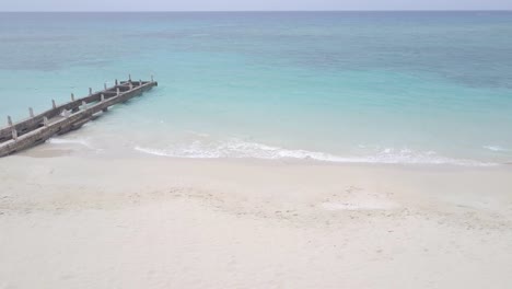 Luftaufnahme-Des-Tropischen-Weißen-Sandstrandes-Von-Jamaika-Mit-Meer,-Sonnenschirm-Und-Stuhl-Am-Privaten-Resortstrand-Ohne-Menschen