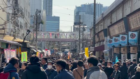 Crowd-of-people-walking-between-skyscrapers-in-the-Tsukiji-Fish-Market,-Tokyo-Japan