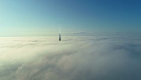 Wolkenkratzer,-Der-Durch-Niedrige,-Flauschige-Wolken-Ragt,-über-Den-Wolken-Fliegt-Und-Die-Blaue-Skyline-Betrachtet