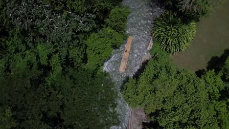 Drone-Aéreo-De-Arriba-Hacia-Abajo-Siguiendo-Un-Bote-De-Balsa-De-Madera-Dentro-De-La-Selva-Tropical-En-Jamaica-Tropical