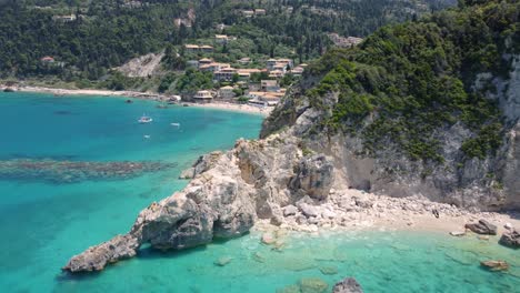 The-holiday-village-of-Agios-Nikitas-nestled-behind-seaside-cliffs,-with-vegetation-and-rocks-along-the-Ionian-Sea-shore,-featuring-an-exotic-beach