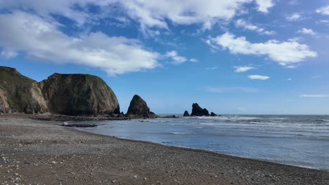 Playa-Tranquila-Durante-La-Marea-Llena,-Mares-Tranquilos-Y-Nubes-Blancas-En-El-Cielo-Azul,-Escena-Pacífica-En-Waterford,-Irlanda.