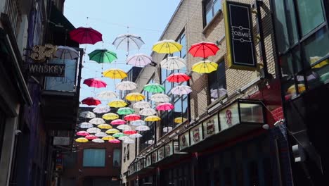 Pan-left-showcasing-the-colorful-street-decor-and-multiple-businesses-on-Anne's-Lane,-Dublin