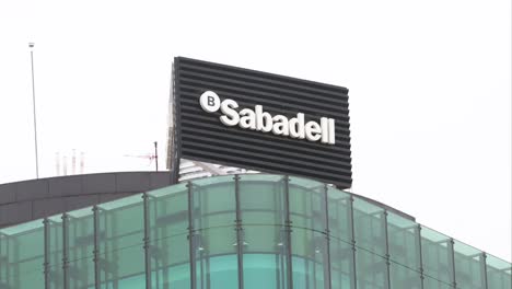 Spanish-multinational-financial-services-company,-Sabadell-Bank,-logo-is-seen-on-top-of-a-building-in-Madrid,-Spain