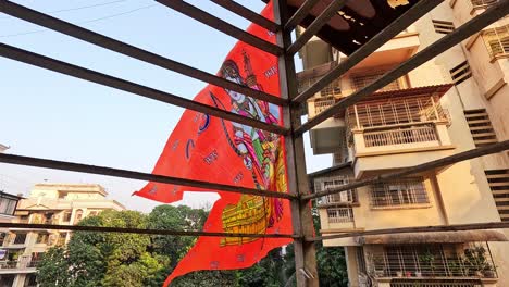 La-Bandera-De-Ram-Mandir-Ondea-Con-Orgullo-En-El-Balcón-De-La-Casa,-Simbolizando-La-Unidad-Y-La-Fe.