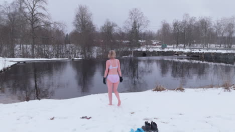 A-happy,-lively-woman-stretches-before-ice-bathing-in-falling-snow,-Sweden